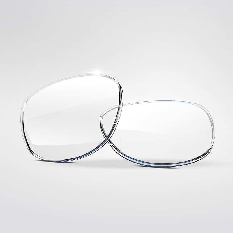 Deux lentilles de lunettes transparentes et claires, aux bords bleutés, légèrement superposées sur un fond gris lumineux.