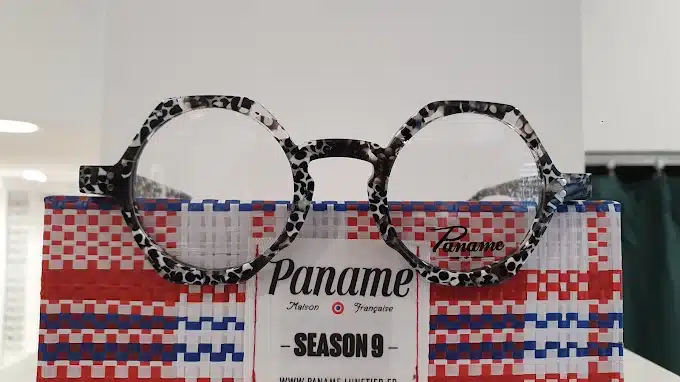 Lunettes de vue Paname à monture mouchetée noir et blanc, posées sur une boîte tressée bleu-blanc-rouge. Texte: 'Maison Française - SEASON 9'.