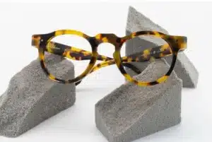 Lunettes de vue P. Perrault à monture épaisse écaille de tortue, posées sur des blocs gris. Inscriptions : + OCTAVE +.
